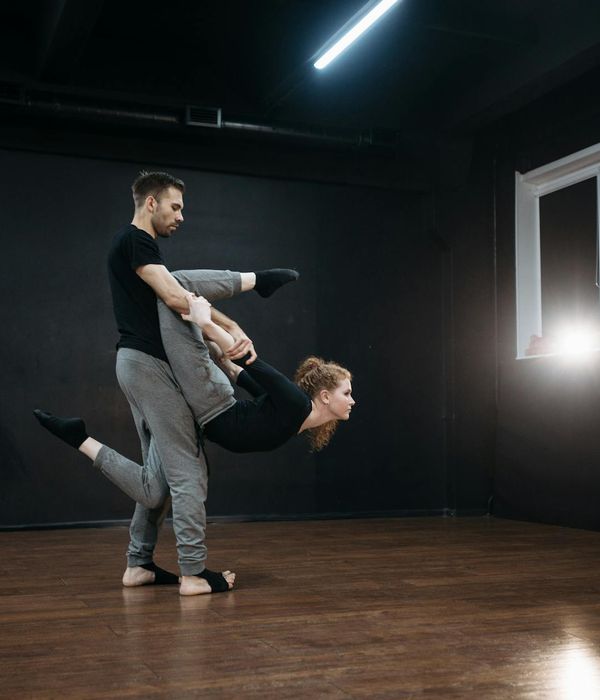 Woman performing a dynamic functional cardio movement in a dark studio.